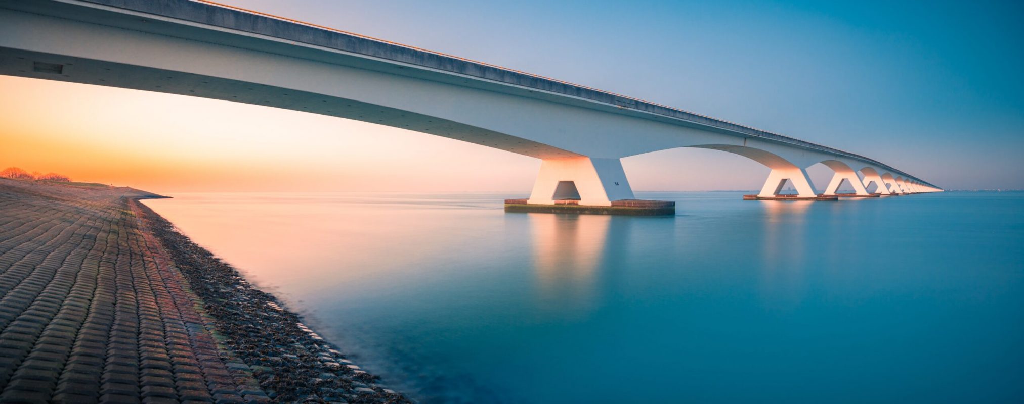 A breathtaking view of a bridge over a peaceful river captured in Zeelandbridge, Netherlands