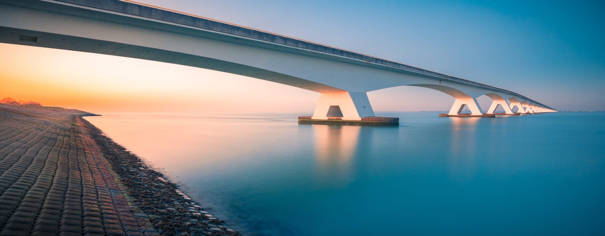 A breathtaking view of a bridge over a peaceful river captured in Zeelandbridge, Netherlands
